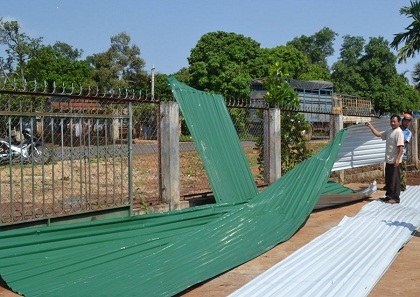 Người dân đang thu dọn mái tôn bị lốc cuốn bay. 