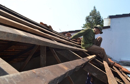 Người dân lợp lại mái ngói sau khi bị lốc xoáy cuốn bay.