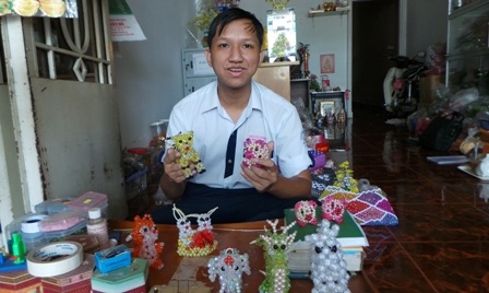 Phước Mai bên những con thú bằng hạt cườm do em làm ra.