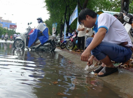 Hố thoát nước bị nghẹt rác, một tình nguyện viên đang xử lí
