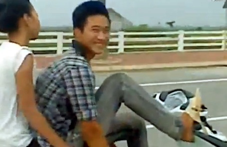 Hà Nội: Lái xe máy bằng chân, chở bạn gái dạo phố - 2 Vừa lái xe vừa cười nói với người đi bên.