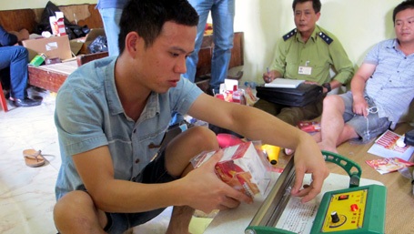 Hà Nội: Phát hiện kho thực phẩm chức năng, bao cao su, thuốc bôi trơn... lậu - 2 Nhân viên cơ sở thực hiện thao tác đóng gói sản phẩm.