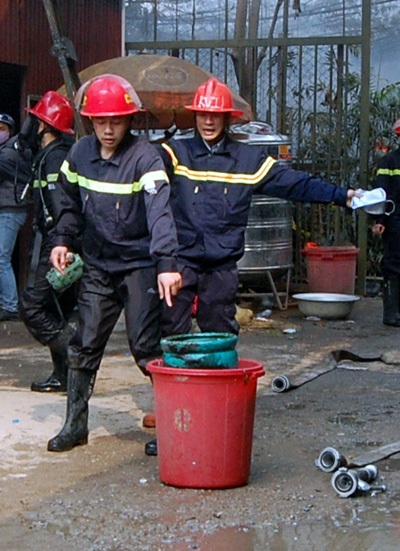 Các chiến sỹ cứu hỏa lao vào đám cháy, ôm bình gas ra ngoài, cho vào thùng nước để xả gas.
