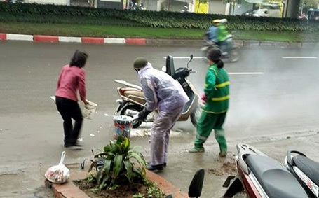 Hà Nội: Hai phụ nữ dũng cảm giải cứu chiếc xe bốc cháy - 1 Hai người phụ nữ giúp chủ xe (áo mưa tím) dập lửa.
