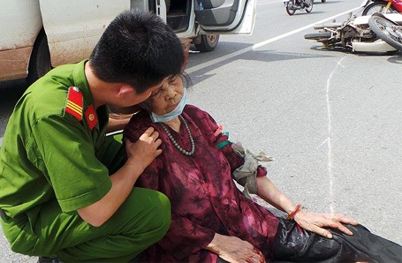 Hà Nội: Tai nạn trọng thương vì vô tình chọc gậy bánh xe - 1 Một chiến sĩ công an động viên bà Hộ. (Ảnh: CTV)