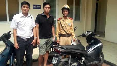 Thiếu úy Phùng Đức Hiếu trao trả chiếc xe cho anh Thắng (giữa) và người thân.