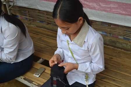 Tỉ mỉ ngồi thêu chiếc quần mới