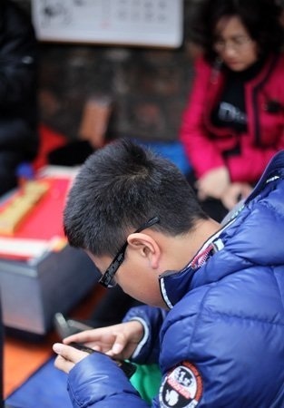 Phố "ông Đồ" thời công nghệ số - 8 Dù là khách hàng hay chủ quán chữ, cứ rảnh rỗi lại dán mắt vào màn hình chiếc điện thoại cảm ứng.