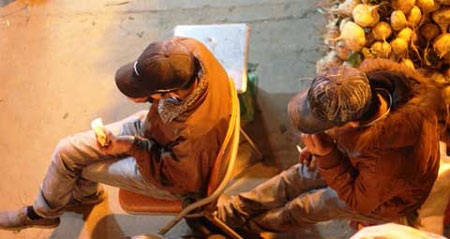 Những đứa bé oằn lưng 'gánh' cả chợ đêm - 2 Hai em nhỏ đang tranh thủ ăn đêm để có sức đấu vật với núi hàng hoá tới sáng