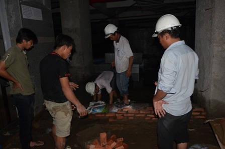 Các công nhân xây tường bao quanh để bơm nước ra ngoài.