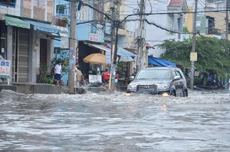 Xe ô tô chạy qua tạo thành những cơn sóng tràn vào nhà dân 2 bên đường