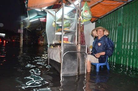 Anh Vu Quang Nhật (49 tuổi) ngồi cả buổi chiều vẫn chưa bán được chiếc bánh nào vì đường ngập
