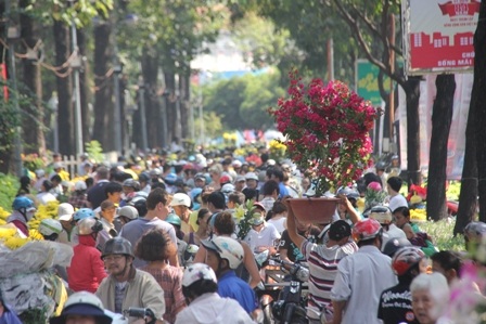 Một người đàn ông bưng chậu hoa len lỏi giữa dòng người