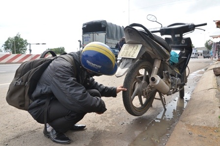 Anh Nguyễn Văn Ngọc đang kiểm tra chiếc xe của mình bị dính đinh.