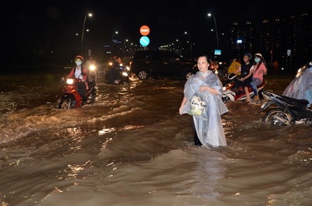 Một người phụ nữ vất vả lội nước thối để về nhà