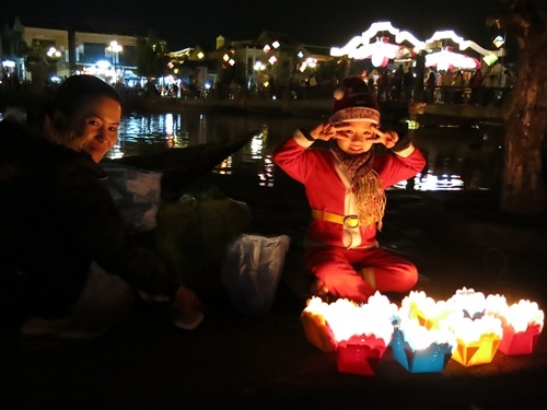 Em nhỏ theo mẹ mưu sinh bên bờ sông Hoài cười hồn nhiên trong sắc áo Noel. (Ảnh: Khánh Hiền)