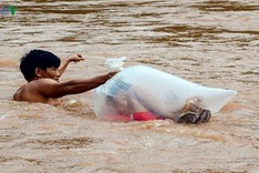 Schoolchildren cross stream in plastic bags